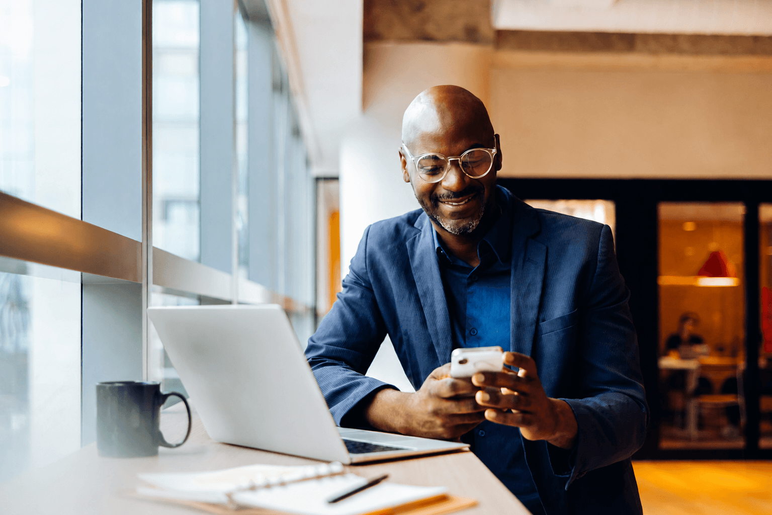 A business owner using his phone beside a laptop